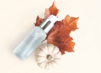 SIG-1273 Concentrated Serum bottle on a leaf next to a white pumpkin on an off-white background.
